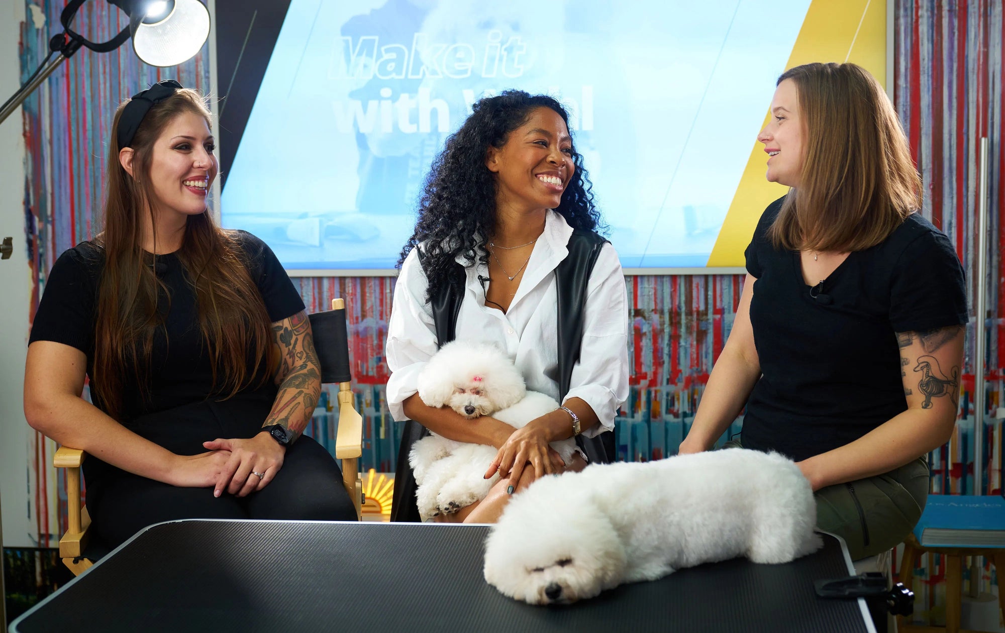 Three women with white dogs in a studio setting